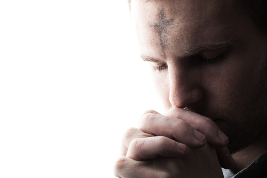 Photo of a man praying with ashes on his forehead